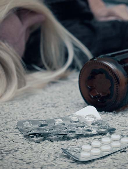 таблетки, бутылка пива и женщина лежат на полу